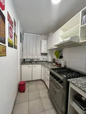a small kitchen with a stove and white cabinets at Departamento Chacabuco in Cordoba