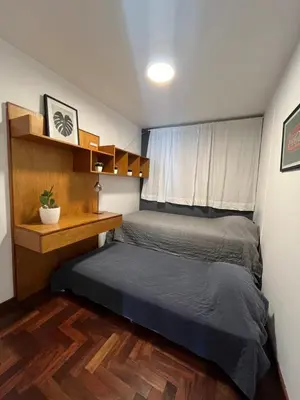 two beds in a small room with a window at Departamento Chacabuco in Cordoba