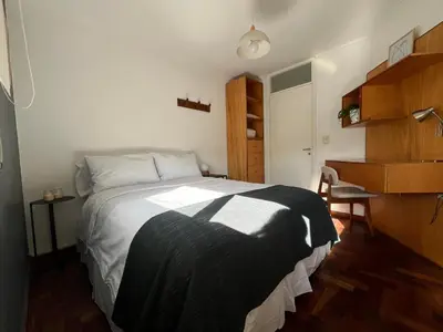 a bedroom with a large bed and a desk at Departamento Chacabuco in Cordoba
