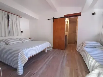 two beds in a white room with wooden floors at Cabaña a Arroyo Cristal in Tanti