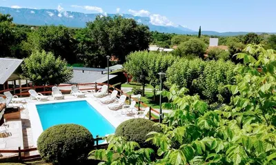 a resort with a swimming pool and chairs and trees at Apart Cabañas La Estancia in Mina Clavero