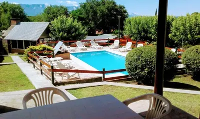 a swimming pool with chairs and a table and a table and a table at Apart Cabañas La Estancia in Mina Clavero