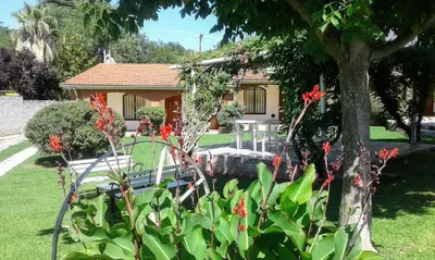 a house with red flowers in a yard at Apart Cabañas La Estancia in Mina Clavero