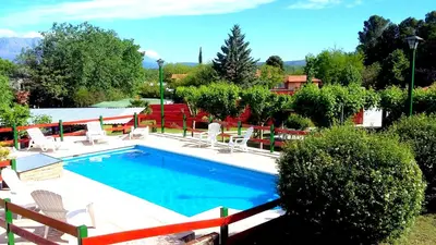 a swimming pool with white chairs at Apart Cabañas La Estancia in Mina Clavero