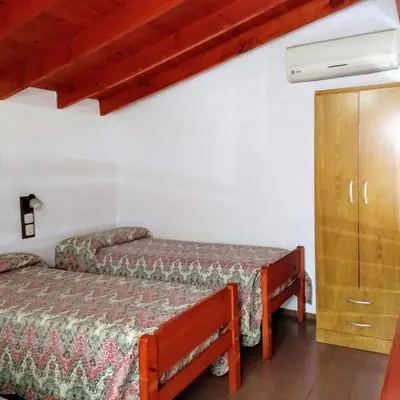 a bedroom with two beds and a cabinet at Apart Cabañas La Estancia in Mina Clavero