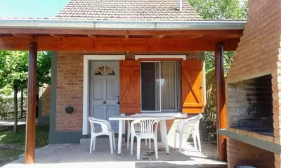 a patio with a table and chairs and a door at Apart Cabañas La Estancia in Mina Clavero
