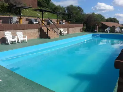 a large blue swimming pool with white chairs in it at La Loma Resort in Merlo