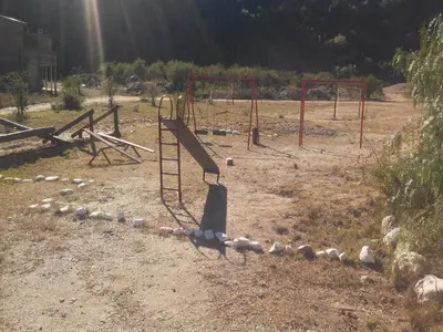 an empty playground with a swing set in a field at La Loma Resort in Merlo