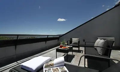 a balcony with two chairs and a table on a roof at Pinares Panorama Suites, Spa & Convention Center in Villa Carlos Paz