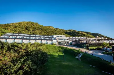 a large building with a mountain in the background at Pinares Panorama Suites, Spa & Convention Center in Villa Carlos Paz