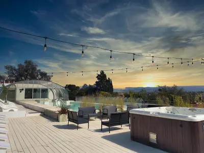 a deck with a hot tub and chairs and a hot tub at Pinares Panorama Suites, Spa & Convention Center in Villa Carlos Paz