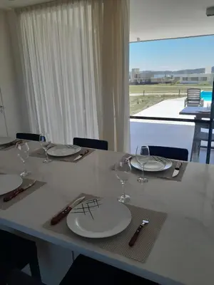 a table with plates and wine glasses on it at Hermosa casa en Puerto del Águila, a orillas del Dique Los Molinos in La Estancia