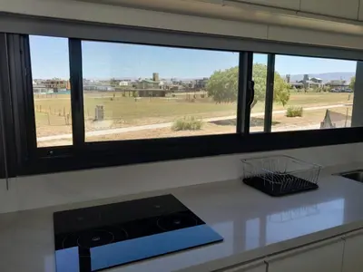 a kitchen window with a view of a field at Hermosa casa en Puerto del Águila, a orillas del Dique Los Molinos in La Estancia