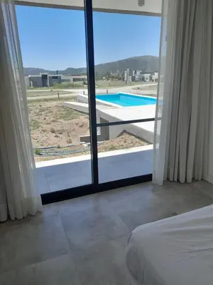a bedroom with a view of a swimming pool through a window at Hermosa casa en Puerto del Águila, a orillas del Dique Los Molinos in La Estancia