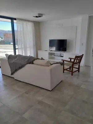 a living room with a white couch and a television at Hermosa casa en Puerto del Águila, a orillas del Dique Los Molinos in La Estancia