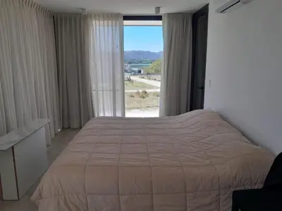 a bedroom with a bed and a large window at Hermosa casa en Puerto del Águila, a orillas del Dique Los Molinos in La Estancia