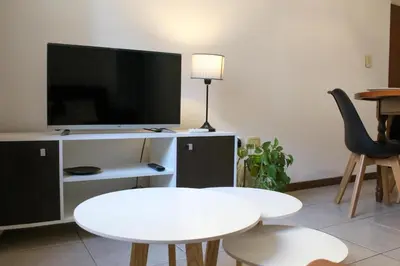 a living room with a white table and a tv at THAYS 70. Hermoso Dpto en Parque de Las Tejas in Cordoba