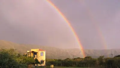 a rainbow in the sky over a house at Las Nubes Apart in Merlo