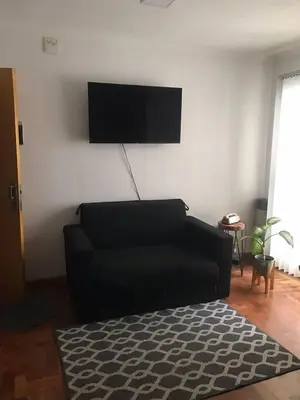 a living room with a black couch and a flat screen tv at Cómodo departamento, excelente ubicacion in Cordoba