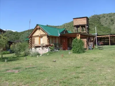 a wooden house with a green roof in a field at Cabañas El Milagro in San Roque