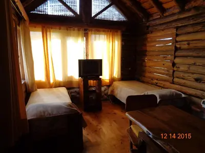 a room with two beds and a television in a log cabin at Cabañas El Milagro in San Roque