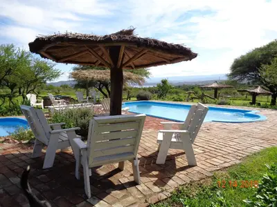 two chairs and an umbrella next to a swimming pool at Cabañas El Milagro in San Roque