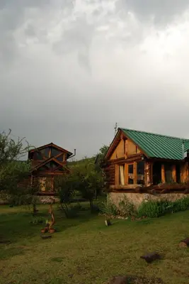 a wooden house with a green roof in a field at Cabañas El Milagro in San Roque