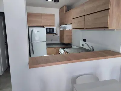 a kitchen with a white refrigerator and wooden cabinets at Increíble dto de 1 dorm en Nva Cordoba in Cordoba