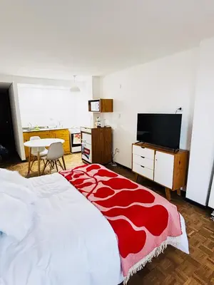 a bedroom with a large bed with a red and white blanket at Hermoso Apartamento en Edificio Saint Michel in Cordoba