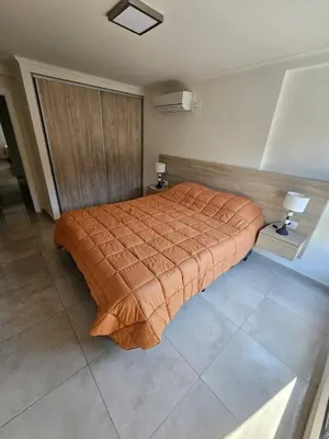 a bedroom with a bed with an orange comforter at Miralejos Apart Triplex in Villa Carlos Paz