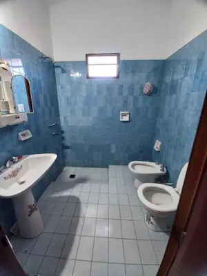 a blue tiled bathroom with two toilets and a sink at CASA ANTONIA in Embalse