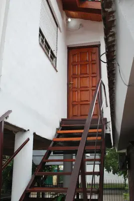 a set of stairs leading to a wooden door at Departamento cómodo y tranquilo in Villa Carlos Paz