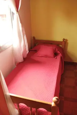 a bedroom with a bed with red sheets and a window at Departamento cómodo y tranquilo in Villa Carlos Paz