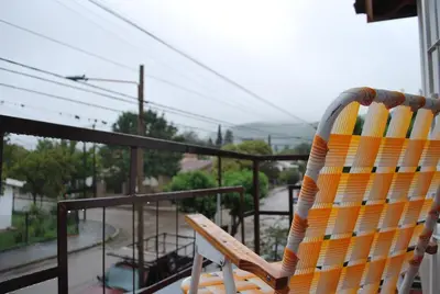 a rocking chair sitting on a balcony overlooking a street at Departamento cómodo y tranquilo in Villa Carlos Paz