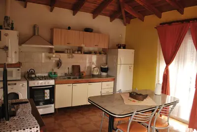 a kitchen with a table and a white refrigerator at Departamento cómodo y tranquilo in Villa Carlos Paz