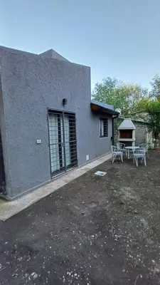 a house with two chairs and a table in a yard at Villa Simona in Santa Rosa de Calamuchita