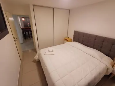 a bedroom with a large white bed with two glasses on it at Hermoso departamento doble be in Cordoba