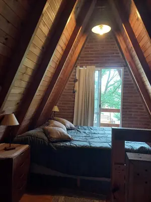 a bedroom with a bed in a attic with a window at Alpinas La Linda in Villa General Belgrano