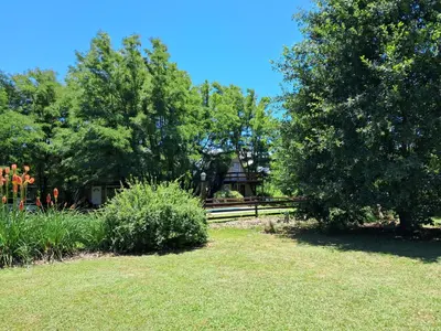 a garden with a house in the background with trees at Alpinas La Linda in Villa General Belgrano