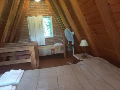 a bedroom in a log cabin with a bed and a window at Alpinas La Linda in Villa General Belgrano