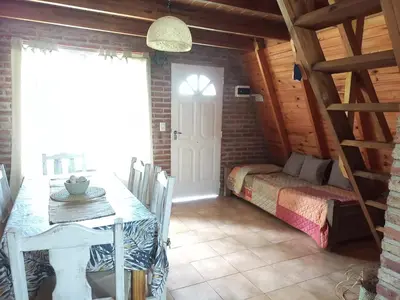 a room with a table and a bed and a window at Alpinas La Linda in Villa General Belgrano