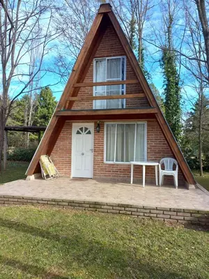a house with a pitched roof with a table and a bench at Alpinas La Linda in Villa General Belgrano