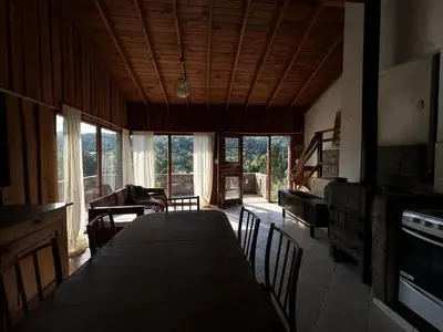 a dining room with a table and chairs and a living room at Casa La Boticaria in La Cumbrecita