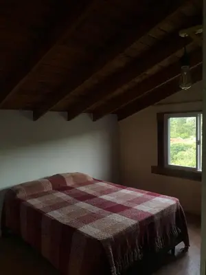 a bedroom with a bed with a plaid blanket on it at Casa La Boticaria in La Cumbrecita