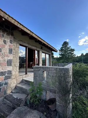 a house with a stone wall next to a building at Casa La Boticaria in La Cumbrecita