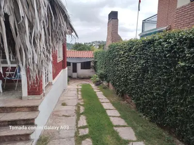 a stone walkway next to a building with a hedge at Alquiler temporario villa Carlos Paz in Villa Carlos Paz