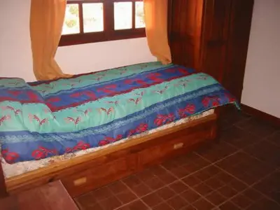 a bed with a blue comforter and a window at Cabañas Oma Lissi in Merlo