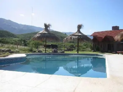 a swimming pool with straw umbrellas and a resort at Cabañas Oma Lissi in Merlo