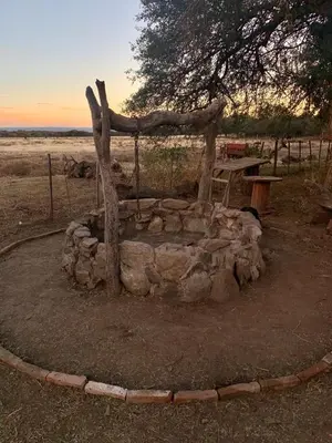 a stone fire pit with a tree and a bench at Portezuelo de árboles in Panaholma