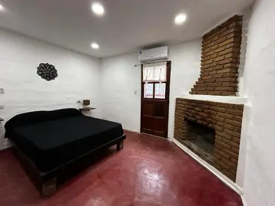 a room with a bed and a brick fireplace at Departamentos MarCor in Nono